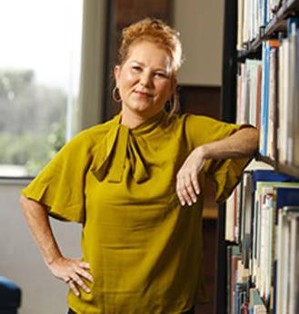 MCC奖学金/经济援助获得者Paula Barlow倚在书架上.